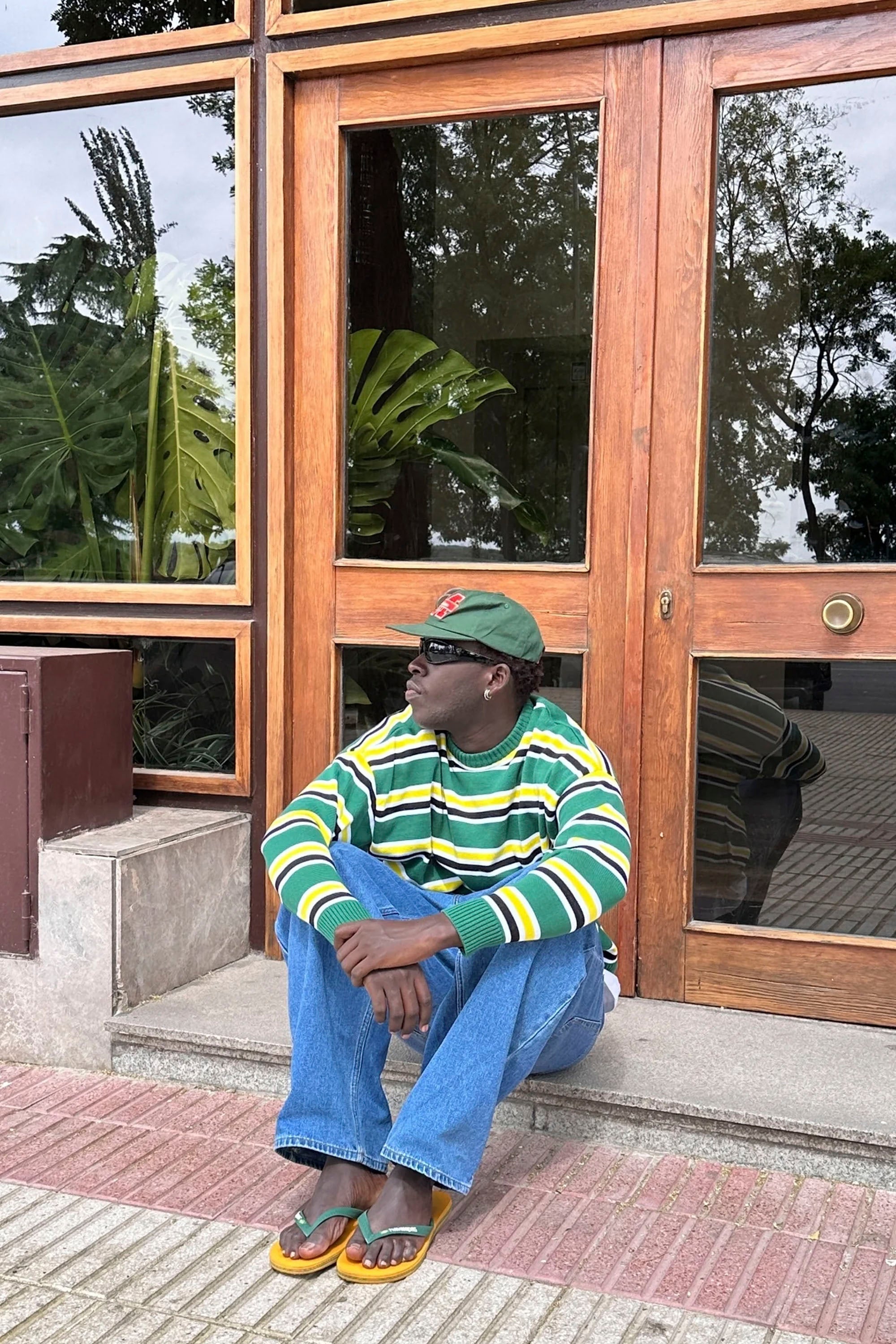 Man sitting on a step in front of a building with Nowhere striped sweater Happylifeshops