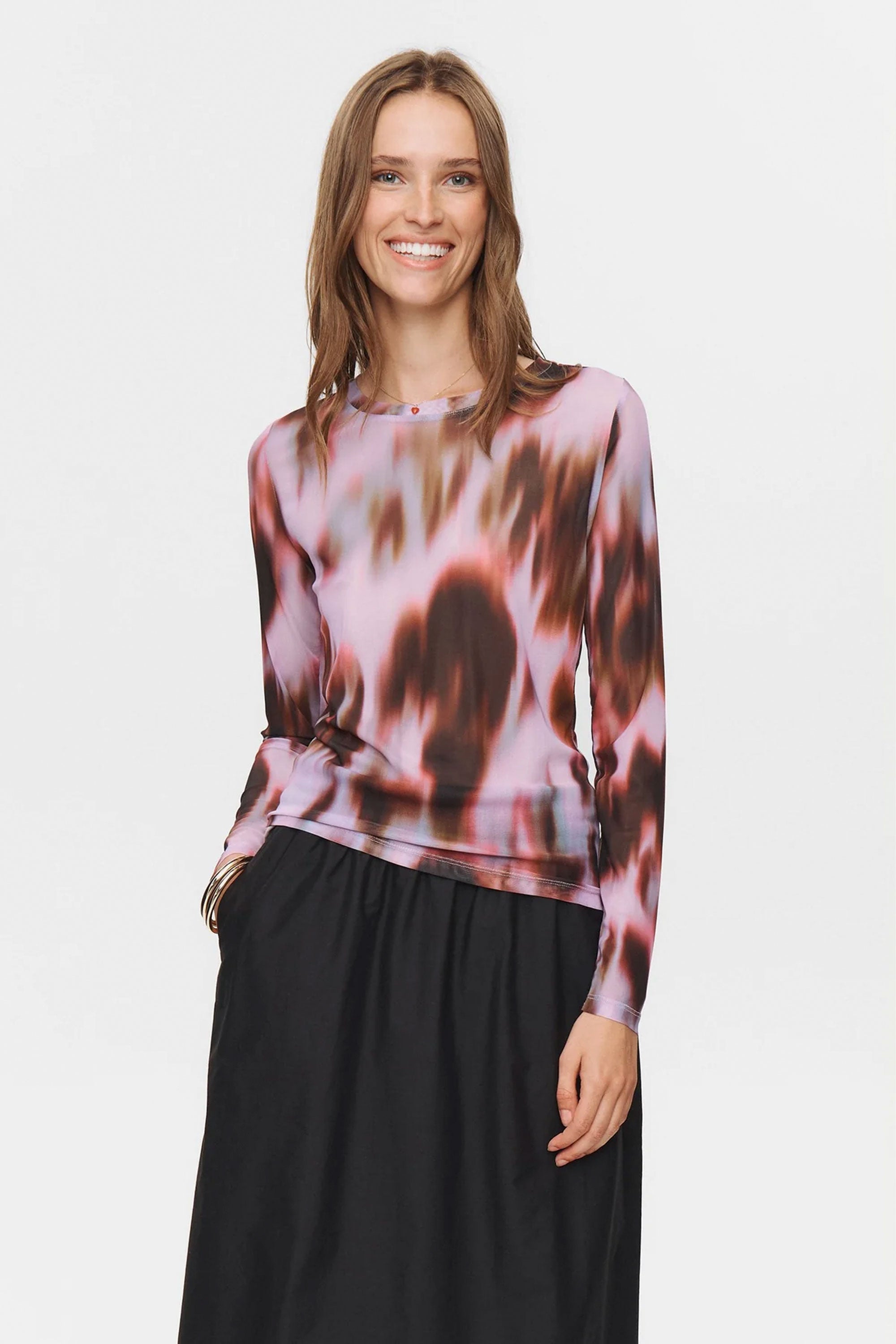 Woman wearing a patterned top and black skirt on a white background